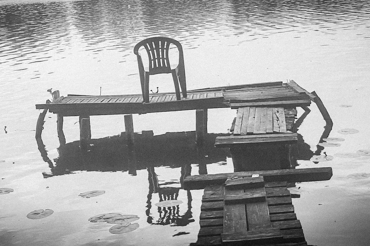 Plastic chair on a broken wooden dock floating on calm water